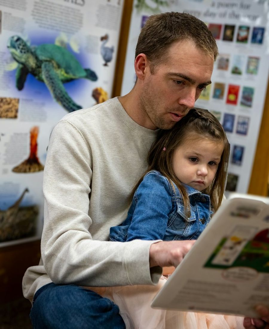 A father reading to his young daughter