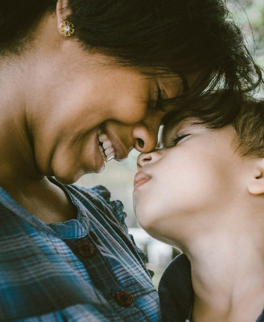 A mother and son touching noses and smiling